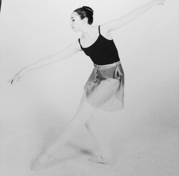 A teen Madison poses in a 2nd arabesque line, looking towards the floor. The image is in black and white.